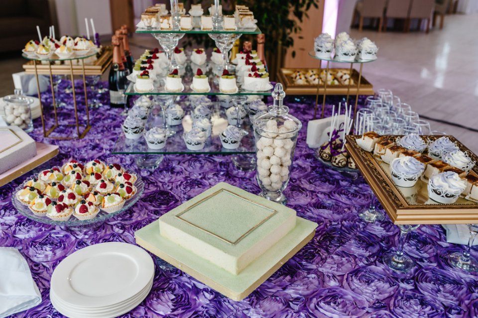 Tavolo dei dolci con dolci su una tovaglia viola. Torte, cupcake e caramelle sono disposti in bella vista.