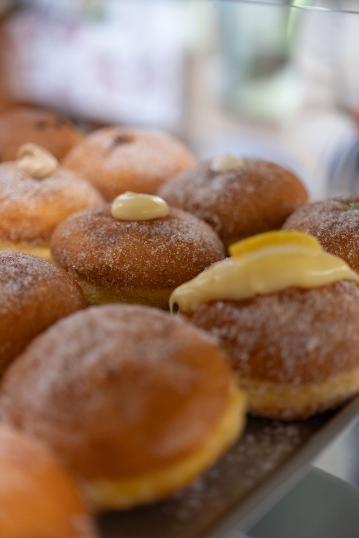 Primo piano di un vassoio di ciambelle rotonde e dorate, ricoperte di panna e zucchero a velo.