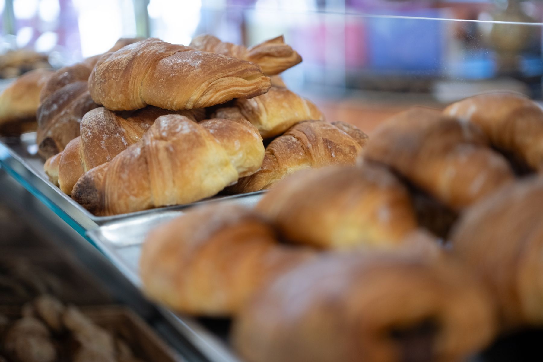 Pila di croissant dorati in una vetrina di panetteria.