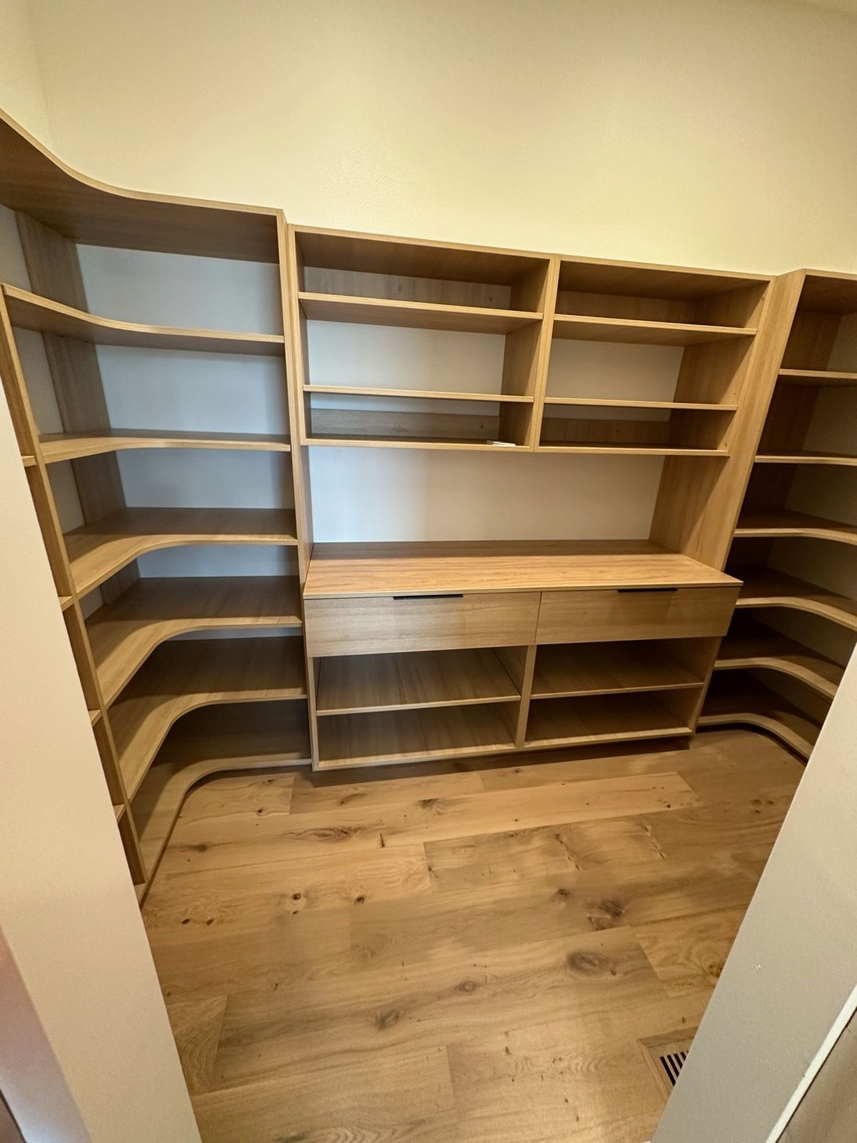 Empty wooden built-in closet with shelves and drawers in a small room