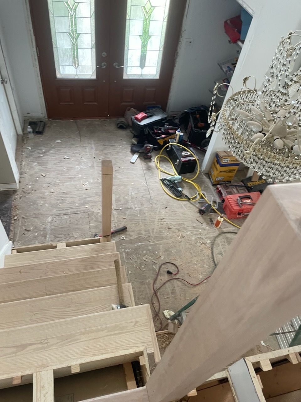 Stairwell under renovation with exposed steps, tools, and materials near a front door.