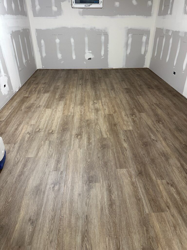 Empty cream-paneled room with arched window and brown hardwood floor