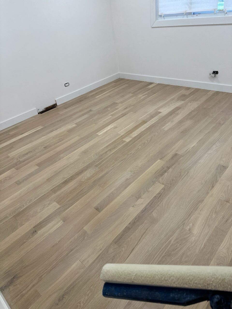 Empty room with light wood flooring, white walls, and a small window.