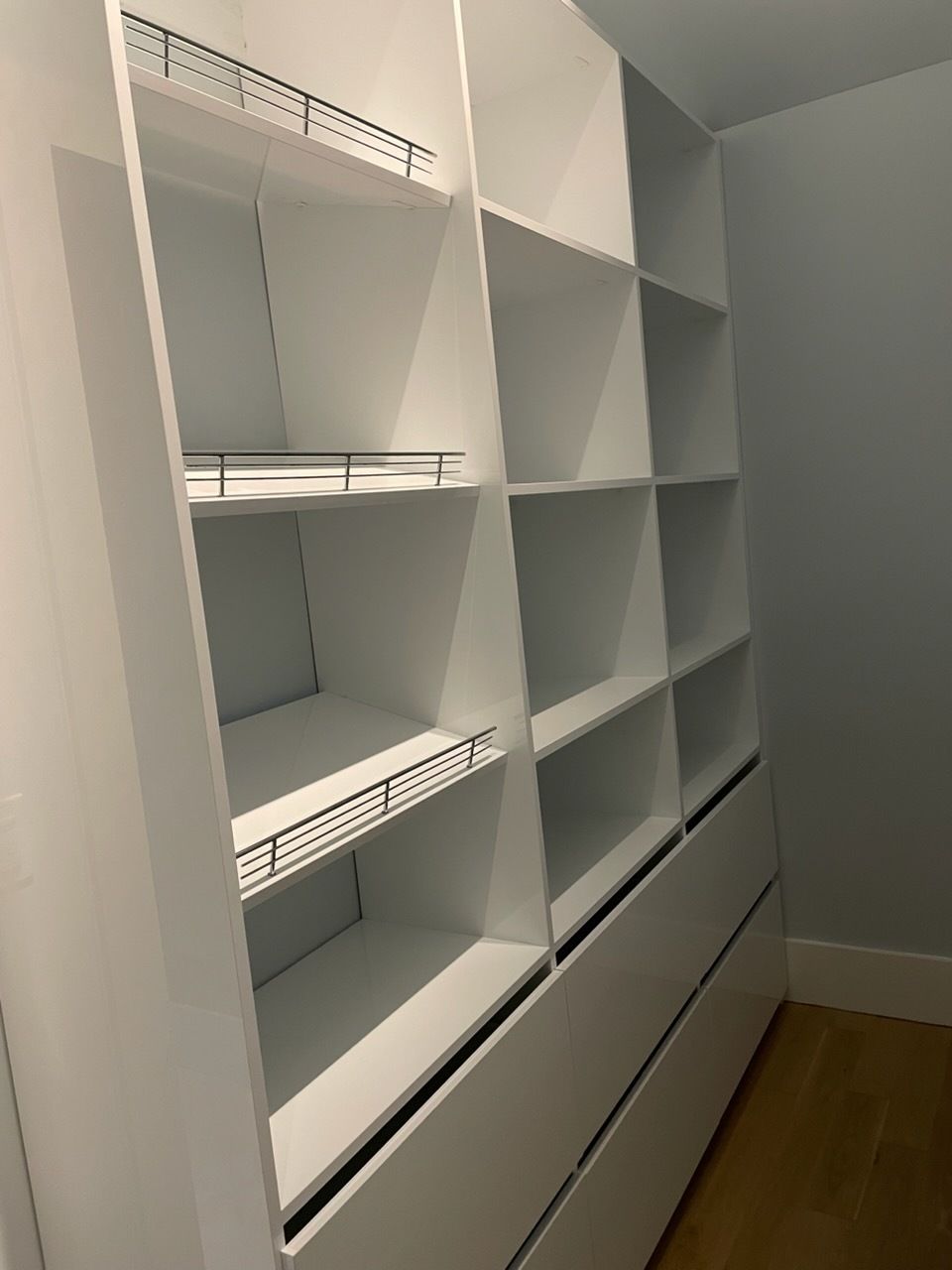Walk-in closet with built-in shelves and drawers, wood flooring, and neutral-toned cabinetry