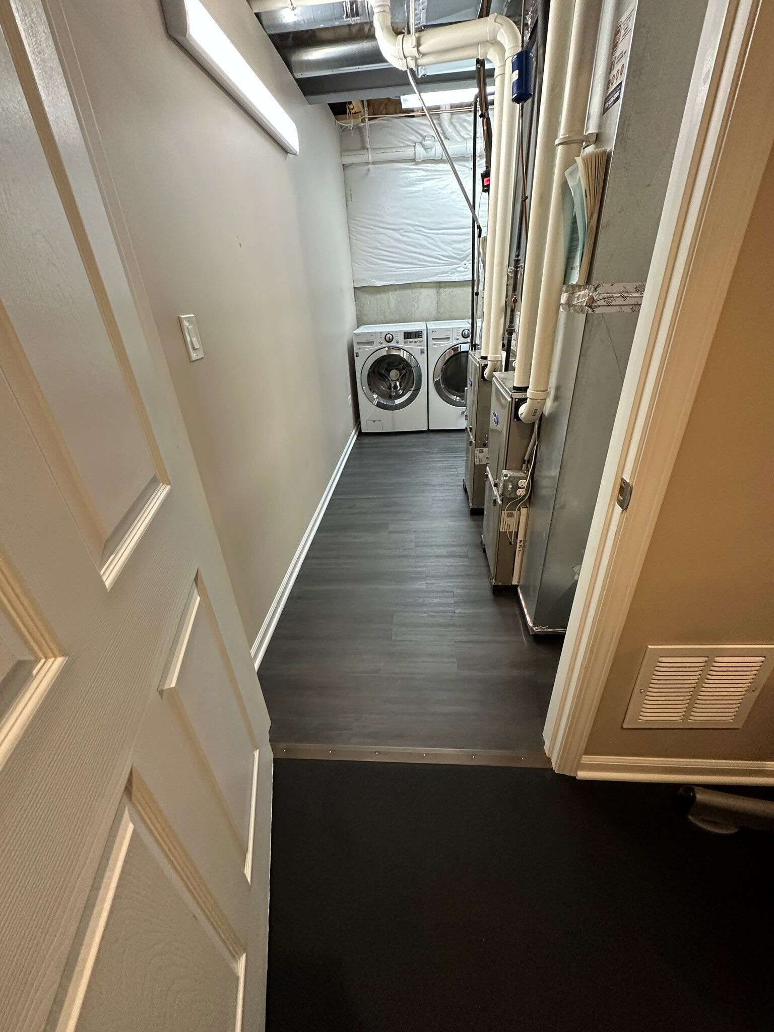 Narrow laundry hallway with washer and dryer at the far end and cabinets along the right wall
