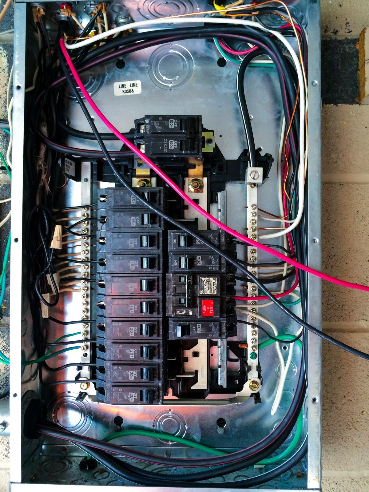 Open electrical breaker panel with exposed wiring and multiple circuit breakers inside a metal box