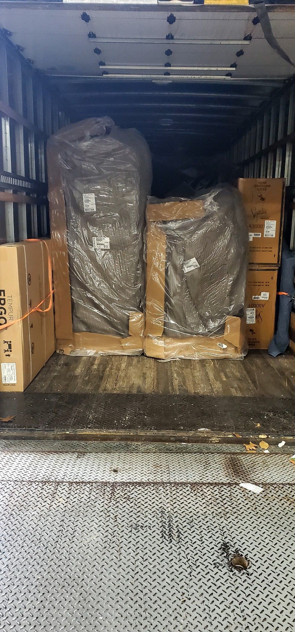 The back of a truck filled with boxes and pallets.