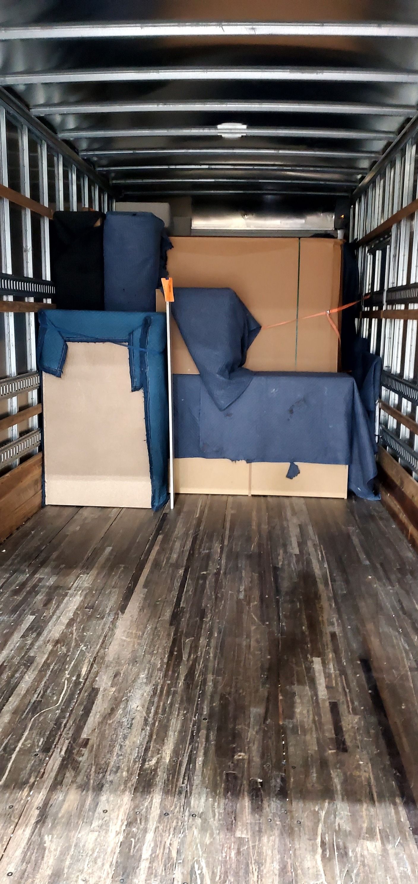 The inside of a moving truck filled with boxes and furniture.
