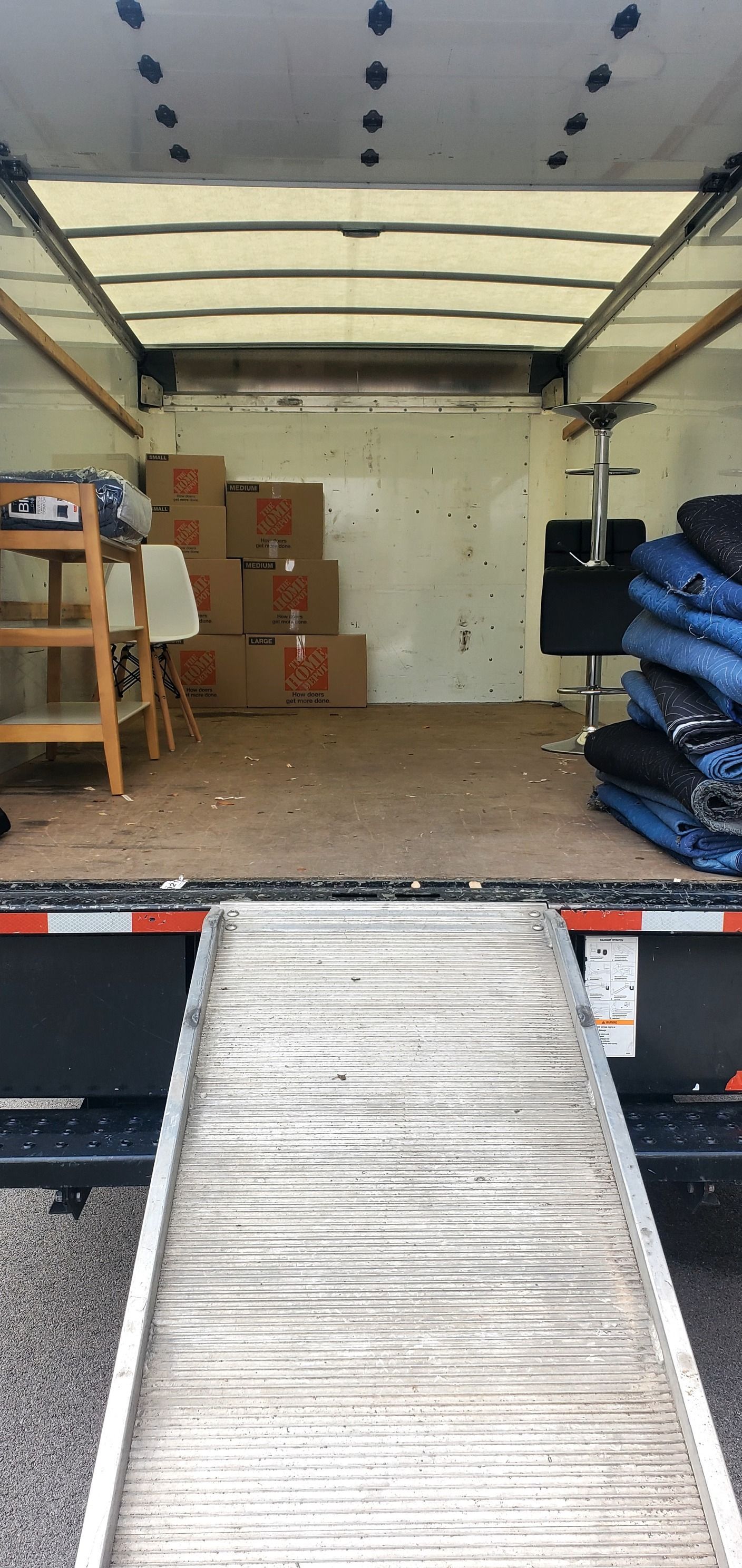 The back of a moving truck with boxes and a ramp.
