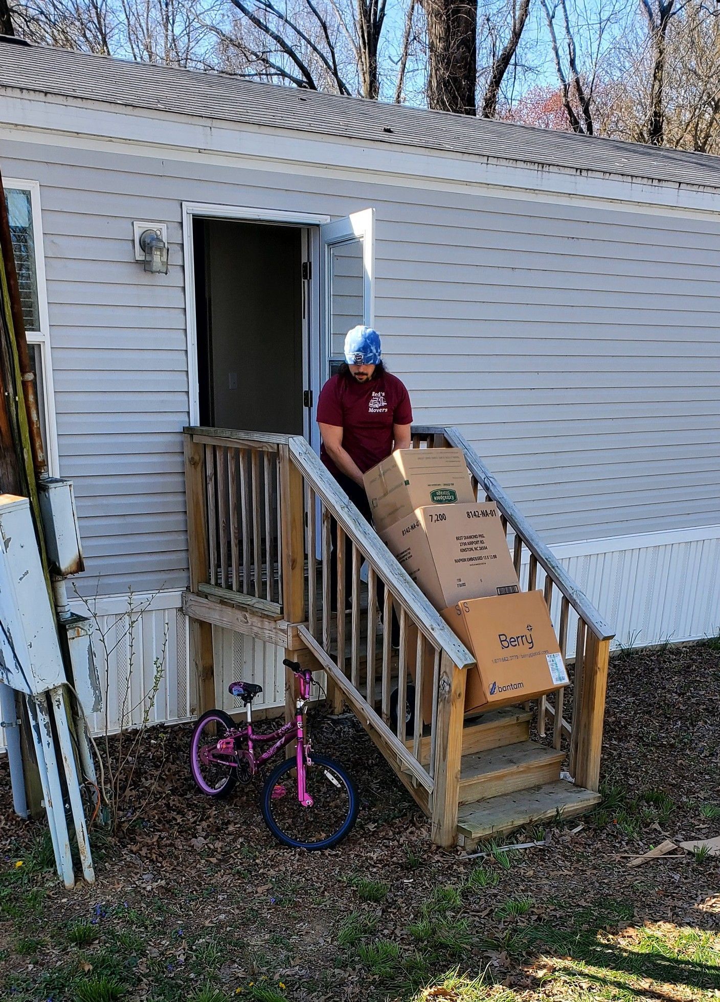 A man is carrying boxes up the stairs of a mobile home.