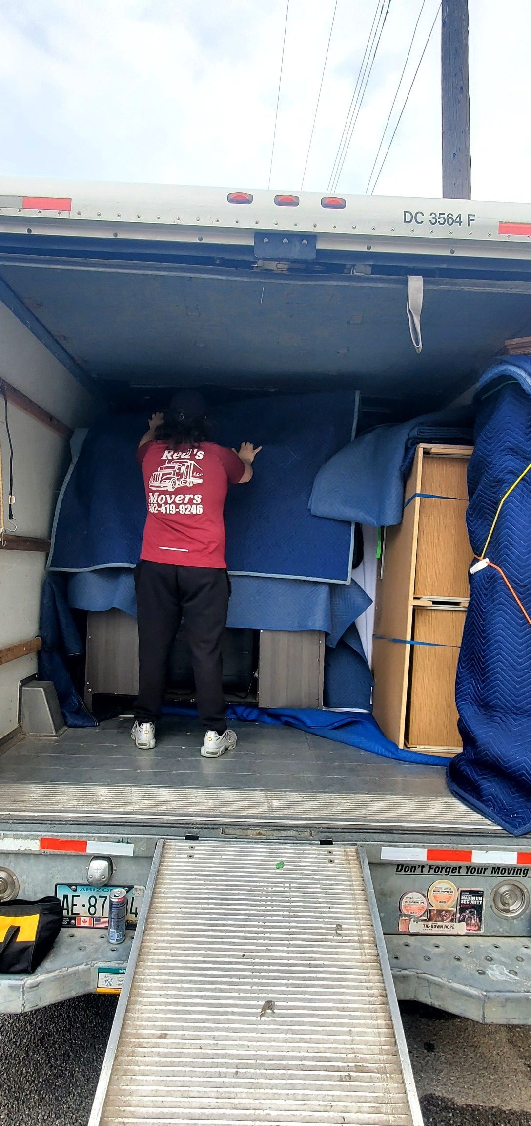 A man is standing in the back of a moving truck.