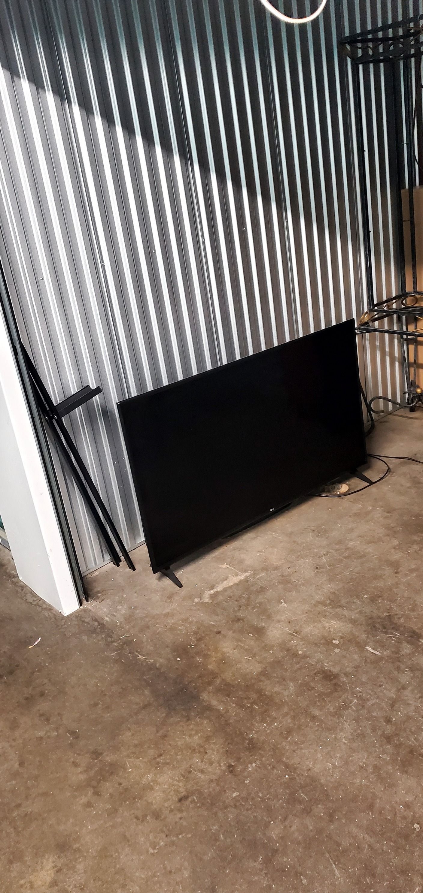 A black tv is sitting on the floor in front of a metal wall.