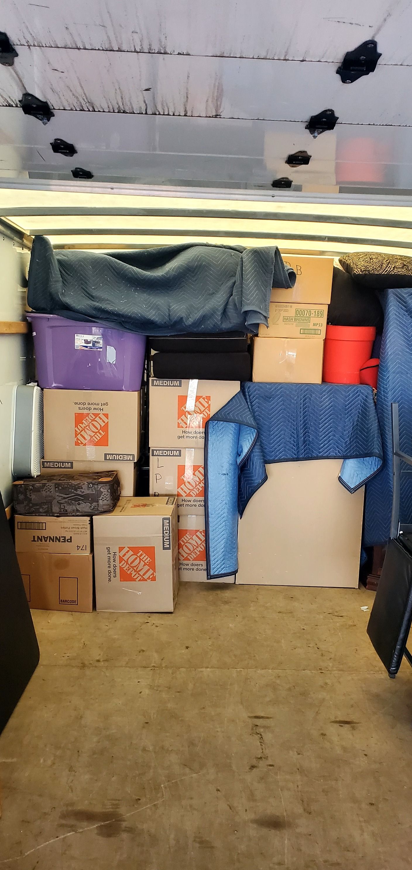 The inside of a moving truck filled with boxes and furniture.