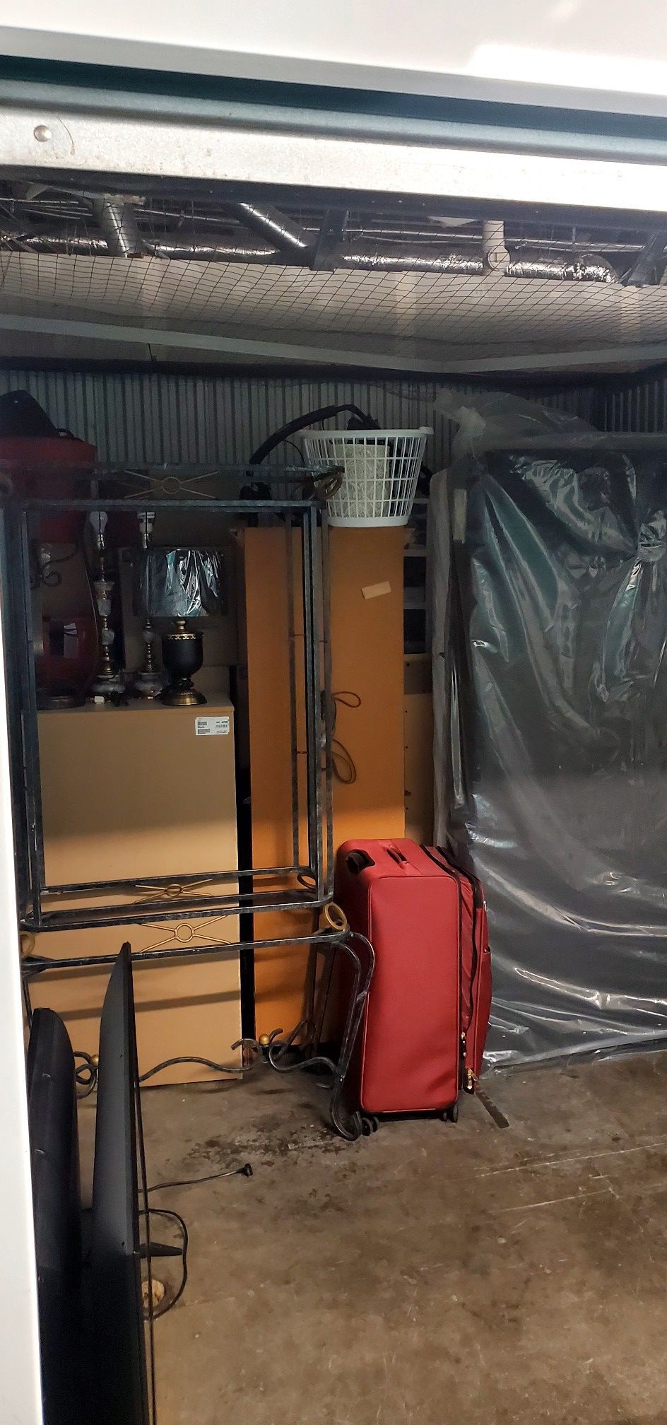 A red suitcase is sitting in a garage next to a television.