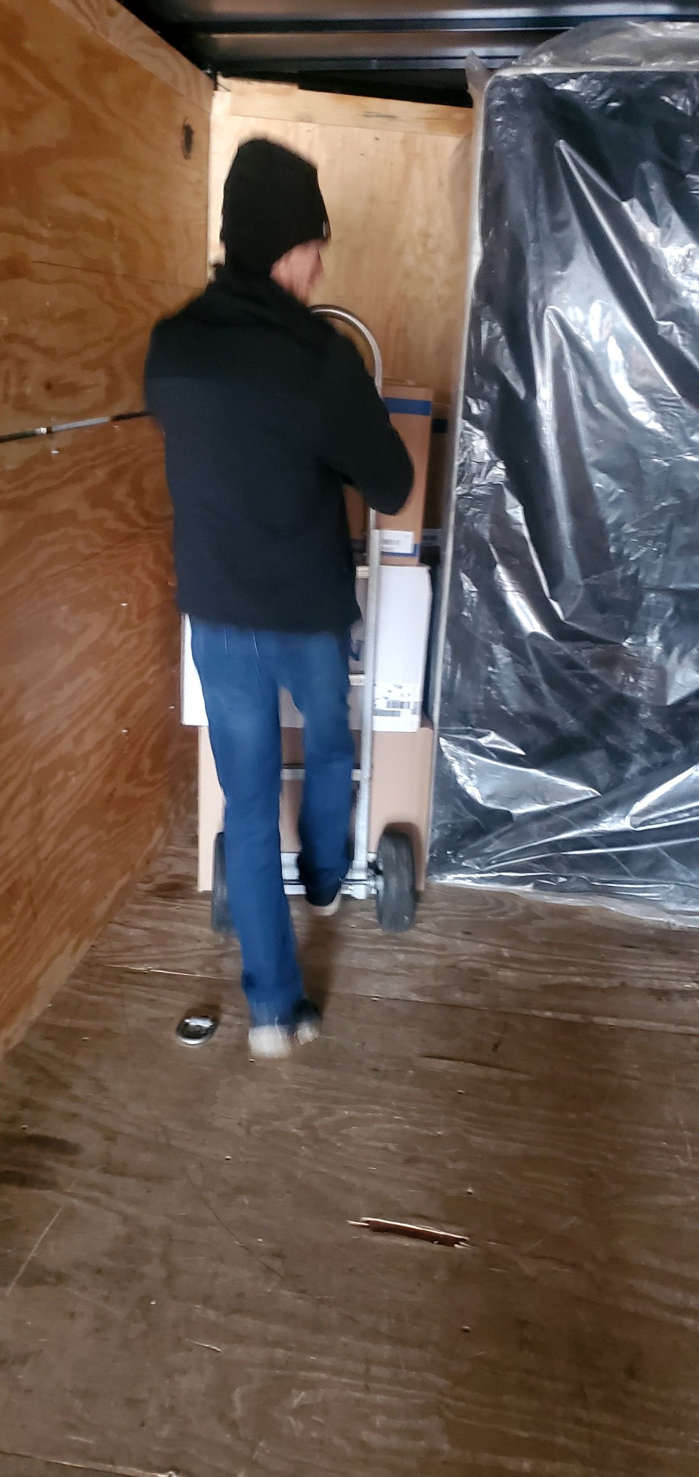 A man is pushing a hand truck in a trailer.