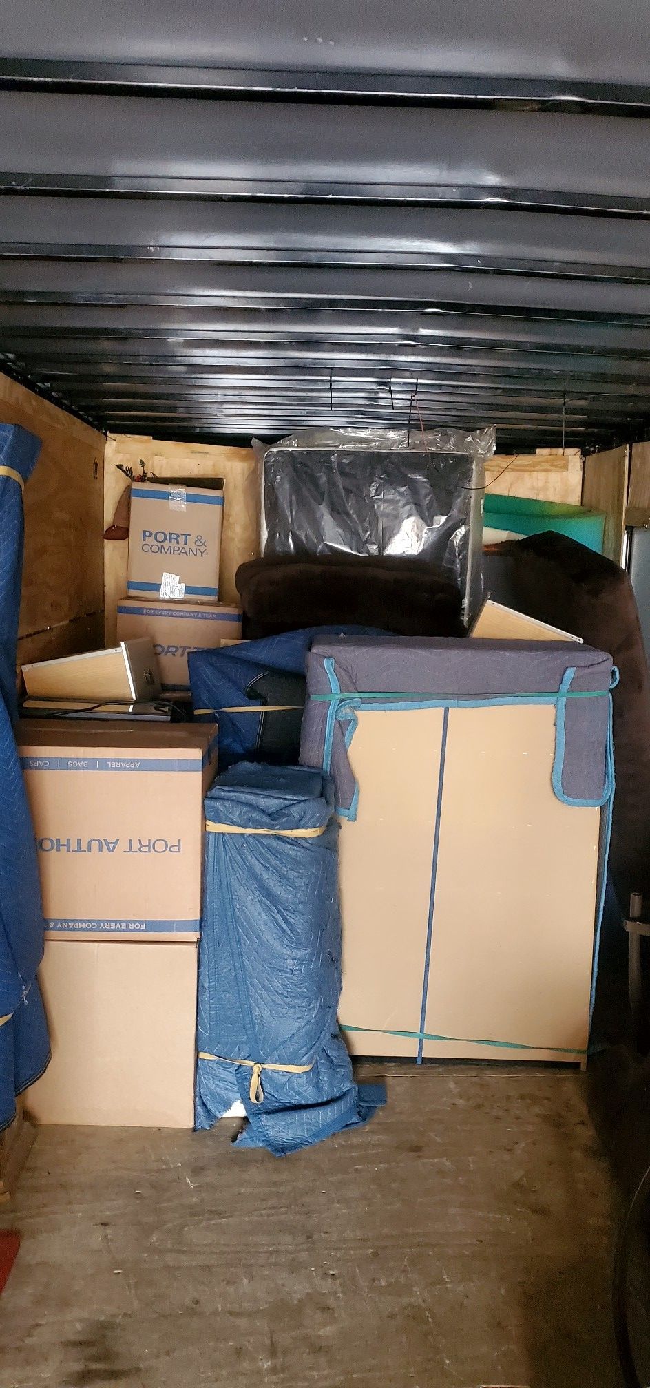 The inside of a moving truck filled with boxes and furniture.