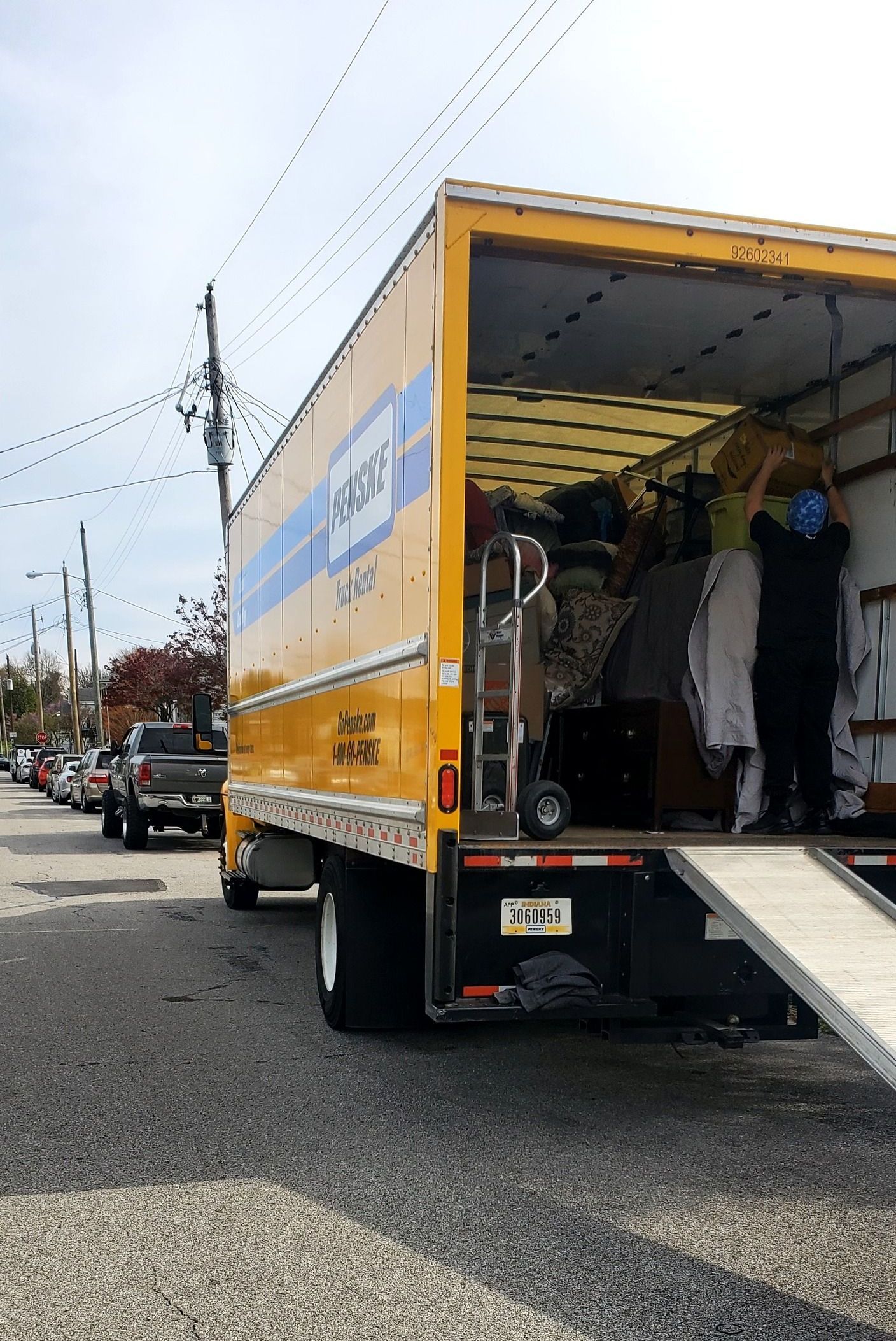 A yellow moving truck is parked on the side of the road.