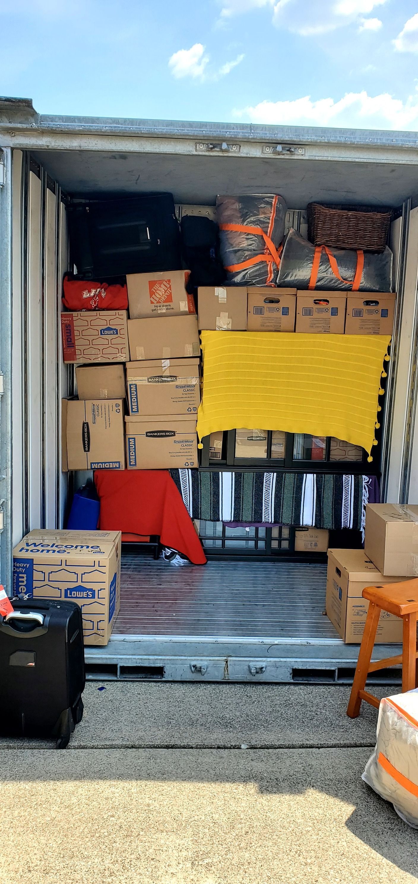 The inside of a moving truck filled with boxes and luggage.
