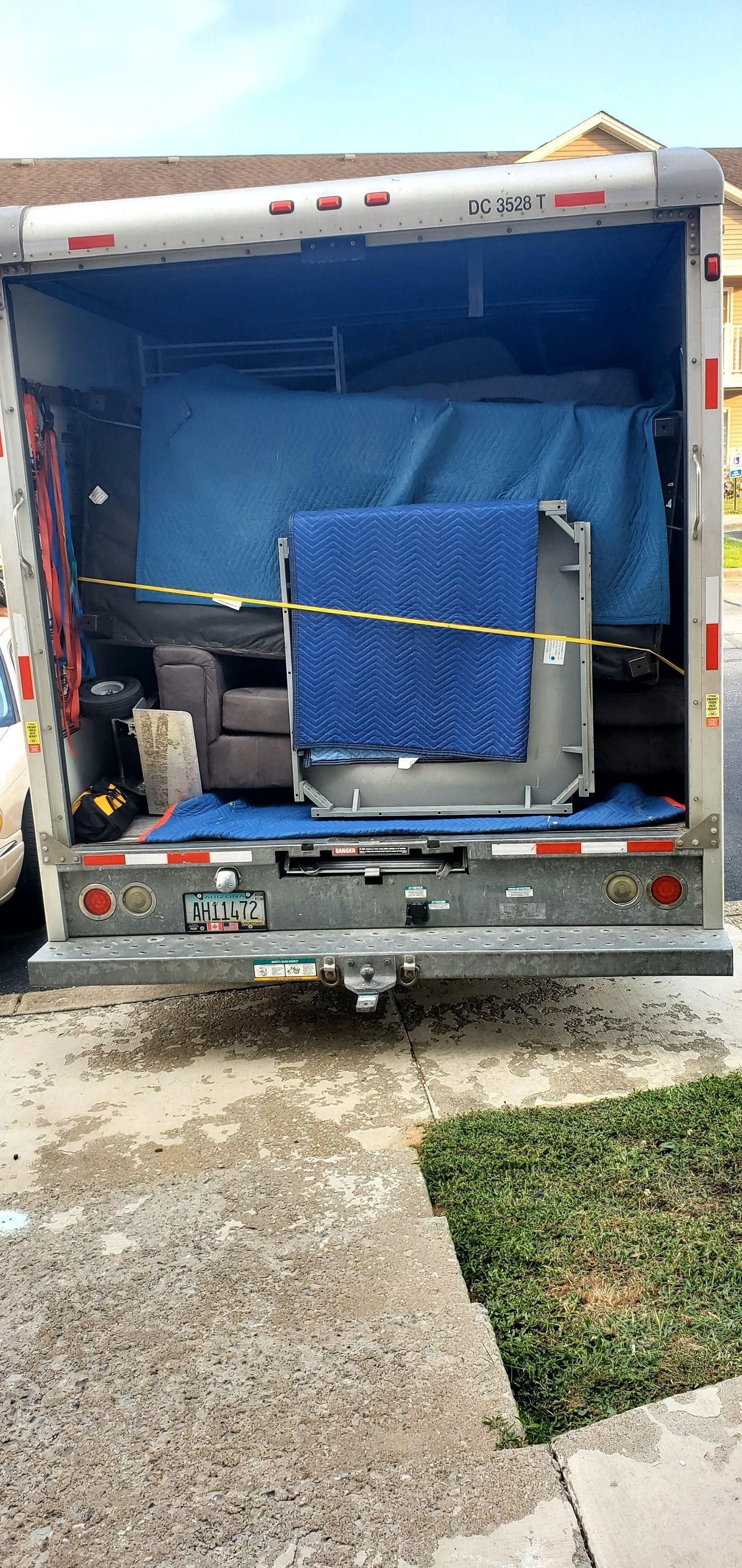 The back of a moving truck is open and filled with furniture.