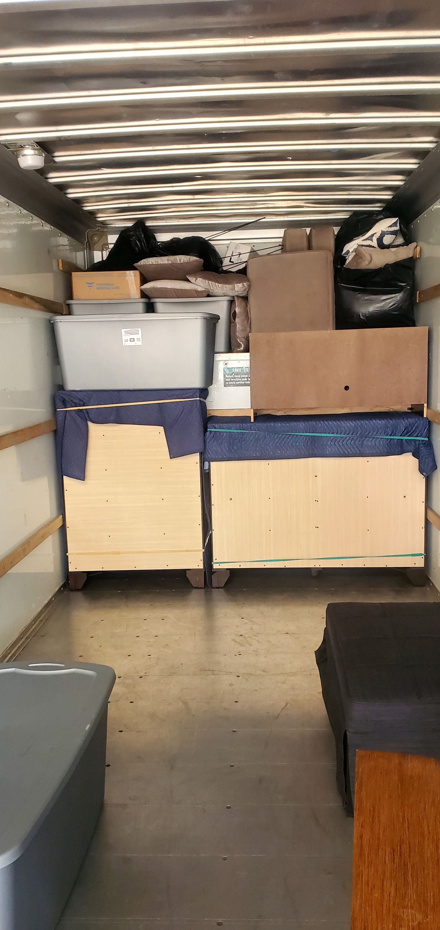 The inside of a moving truck filled with boxes and furniture.