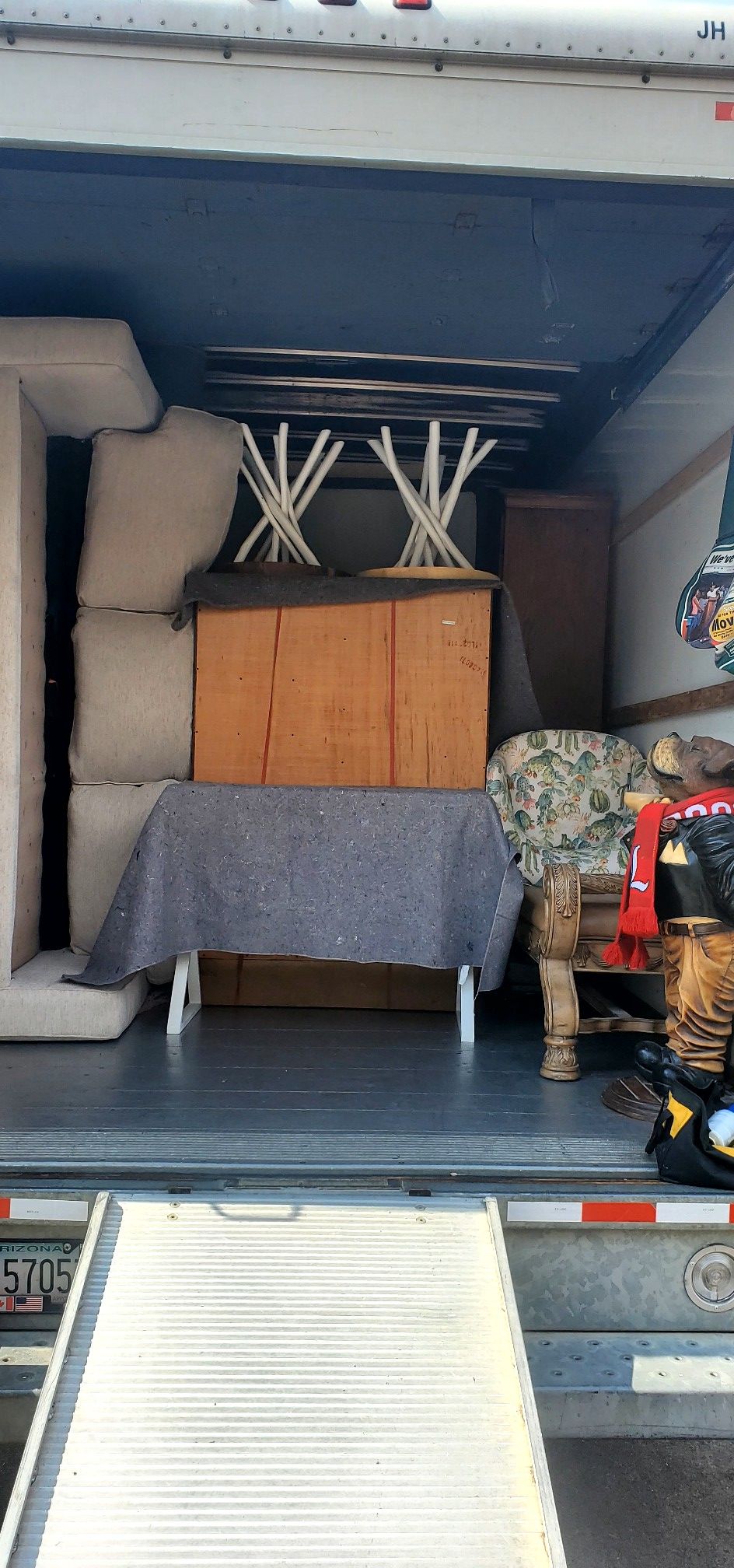 The back of a moving truck filled with furniture and a table.
