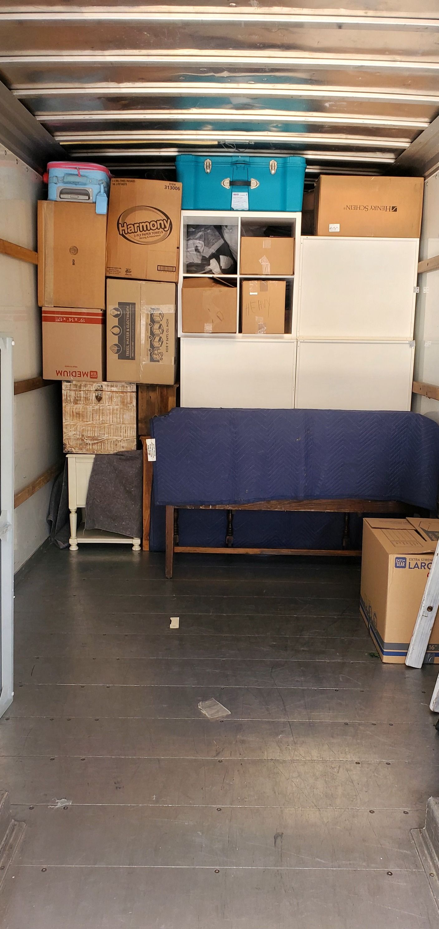 The inside of a moving truck filled with boxes and furniture.
