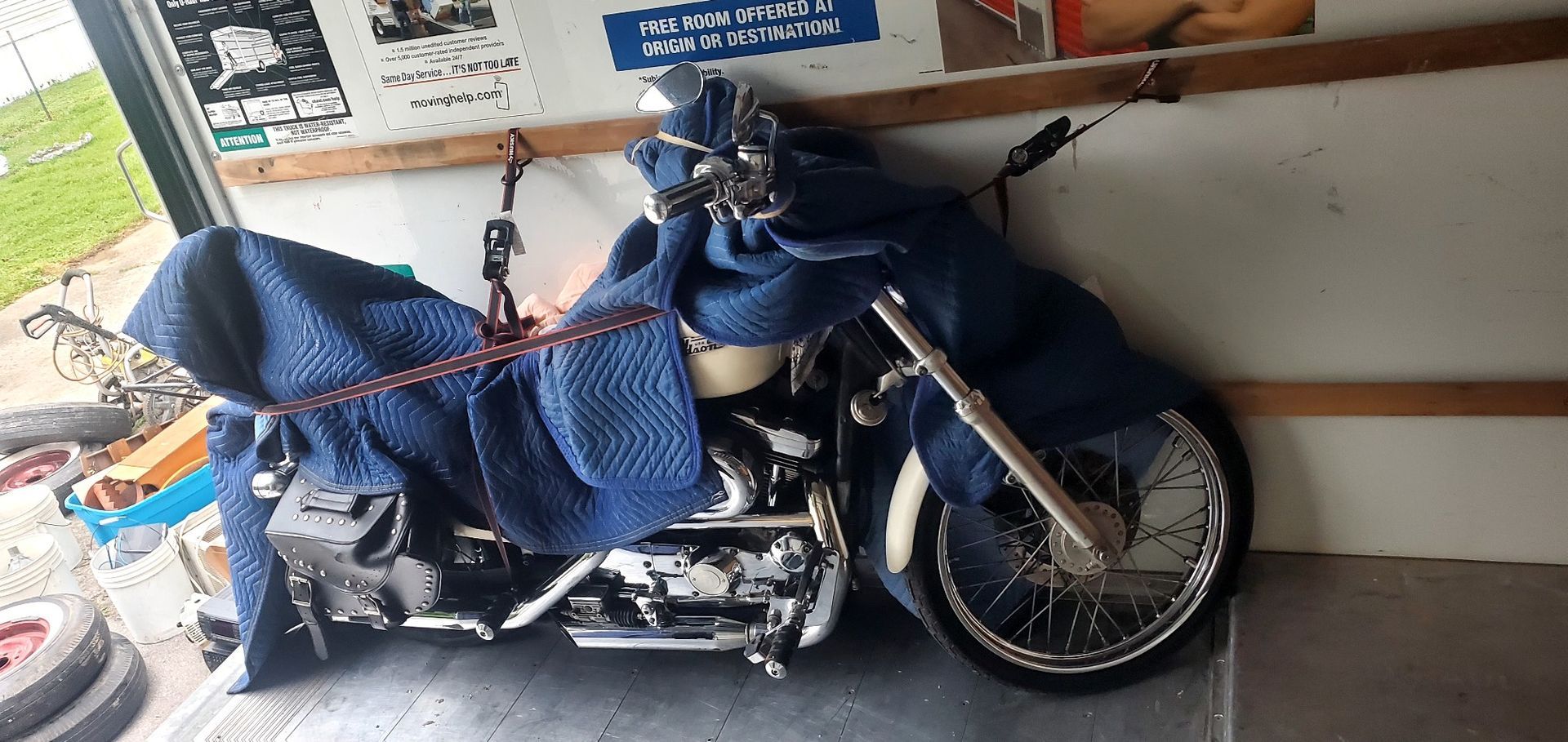 A motorcycle is wrapped in a blue blanket in a garage.