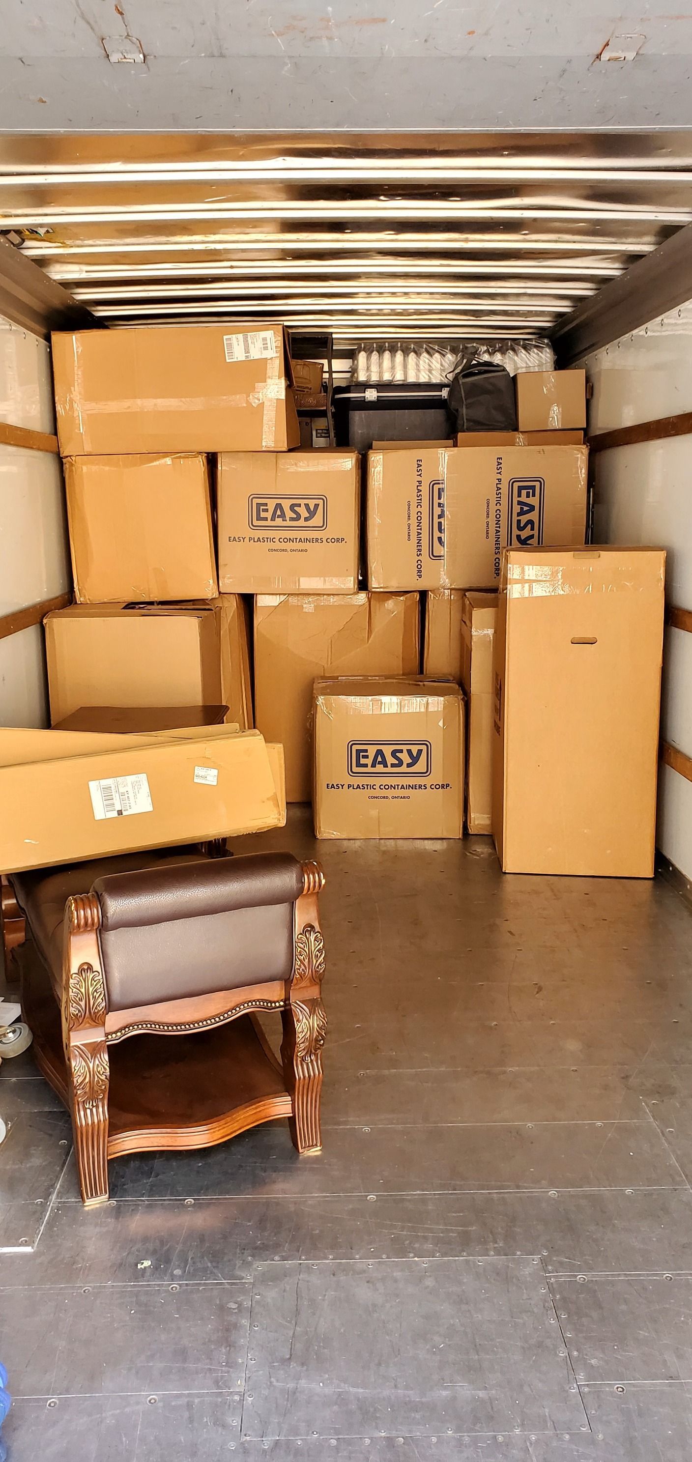 The inside of a moving truck filled with boxes and furniture.