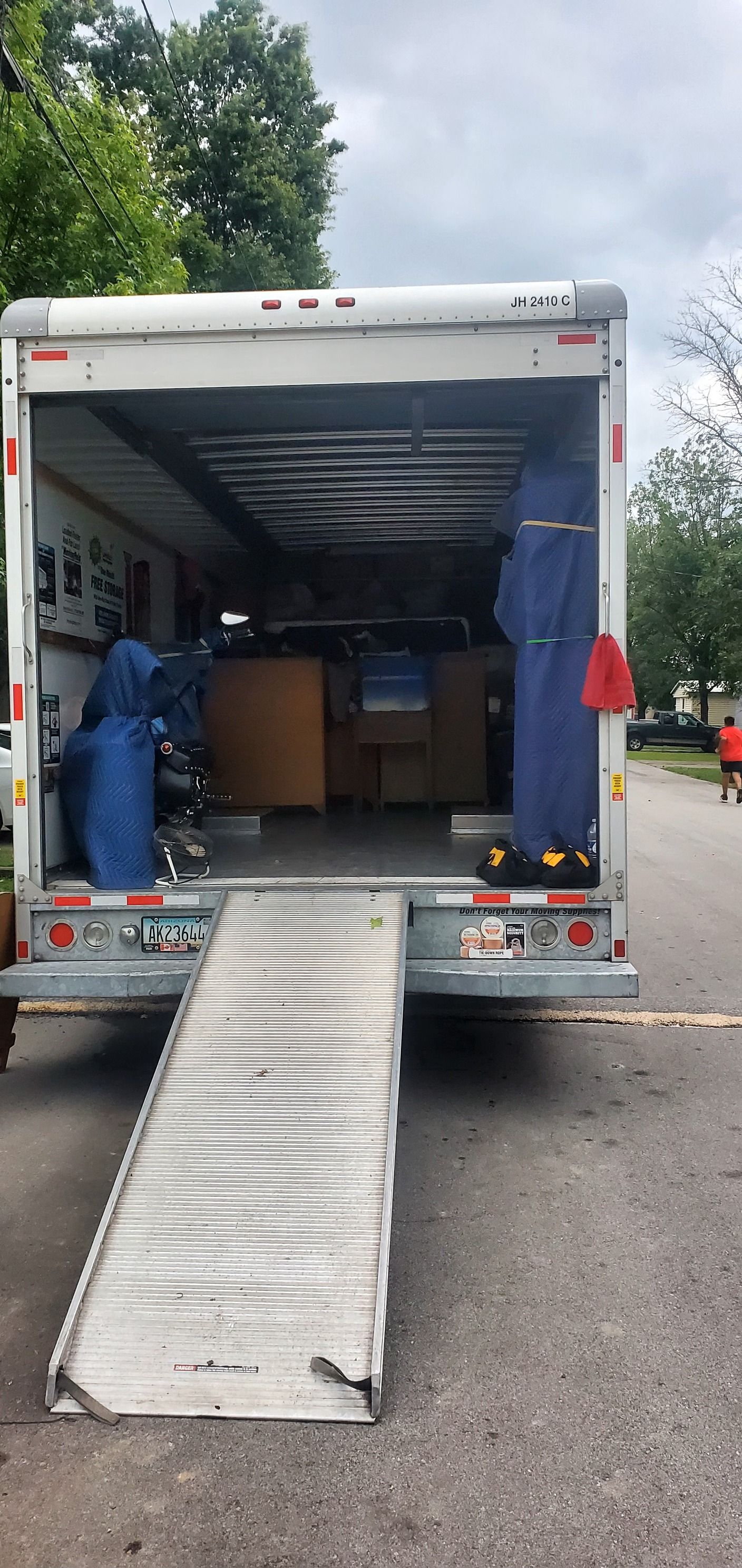 The back of a moving truck with the door open and a ramp.
