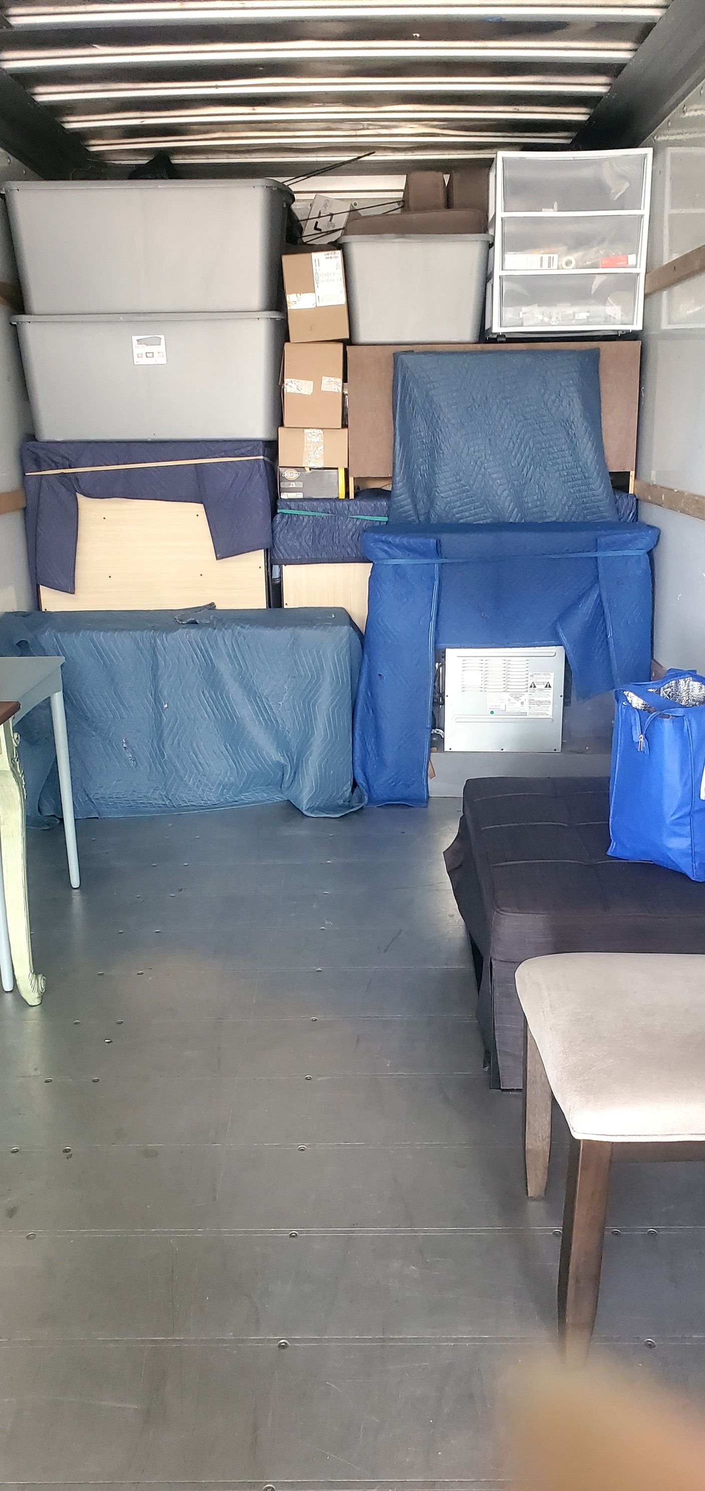 The inside of a moving truck filled with furniture and boxes.