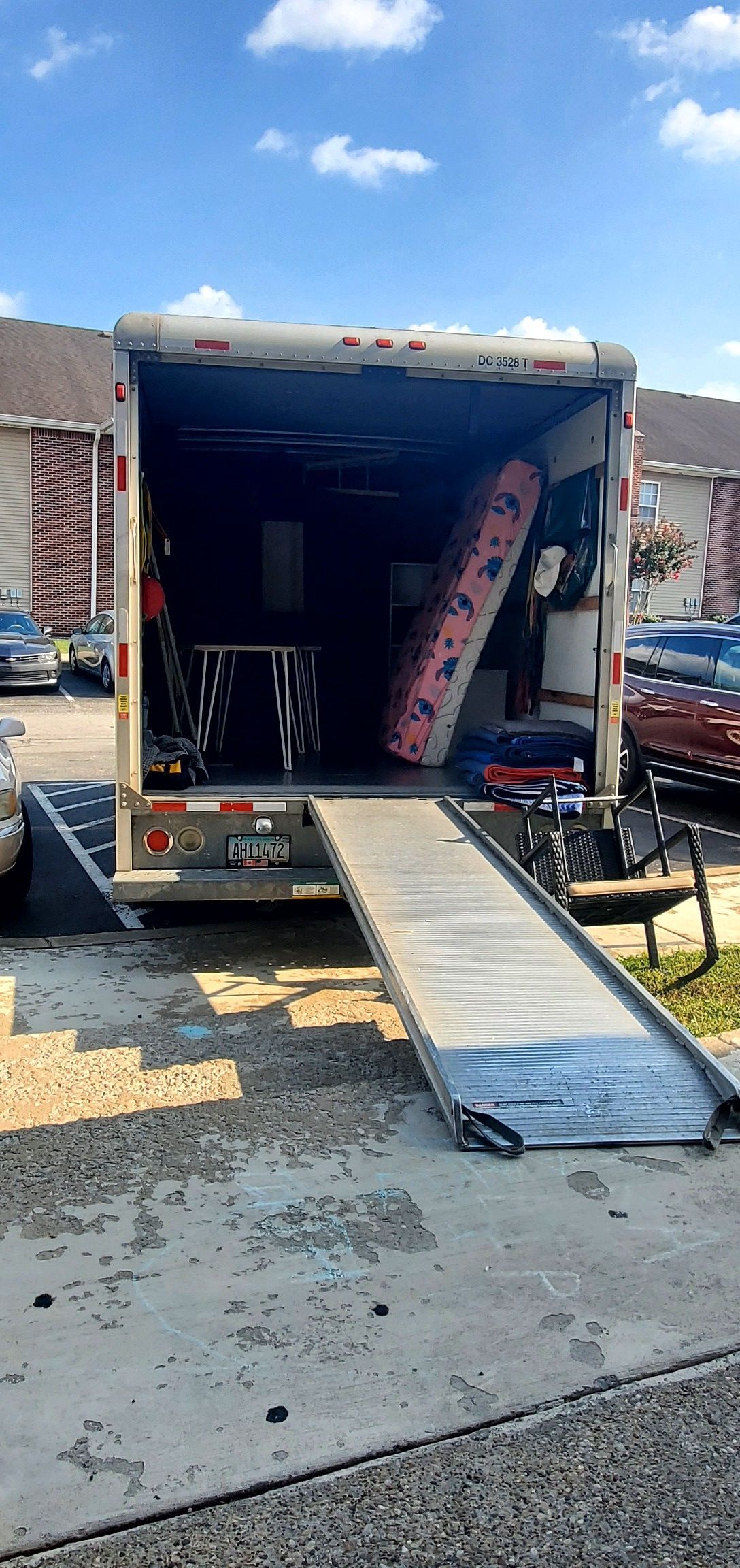 A moving truck is sitting on a ramp in a parking lot.