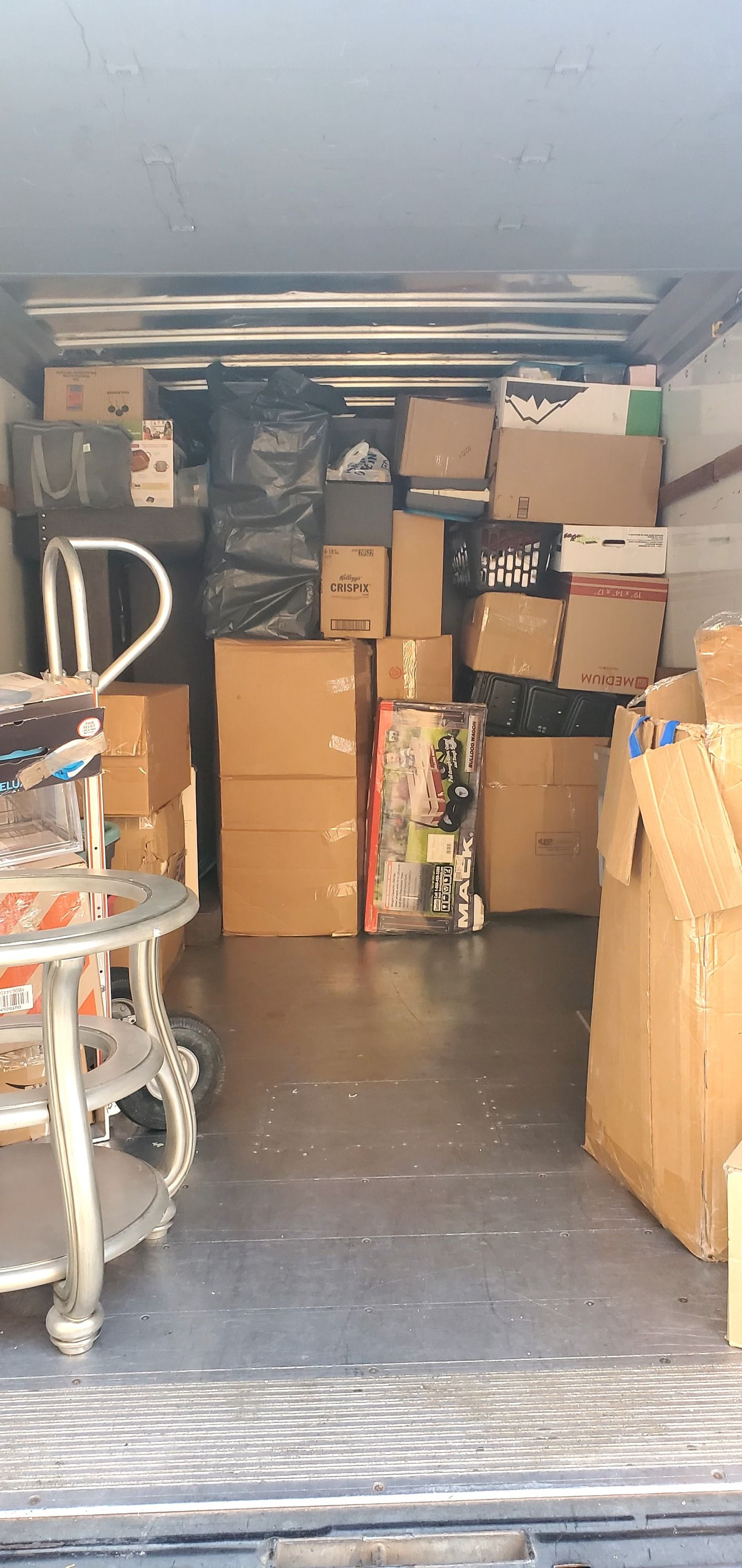 The inside of a truck filled with boxes and a cart.
