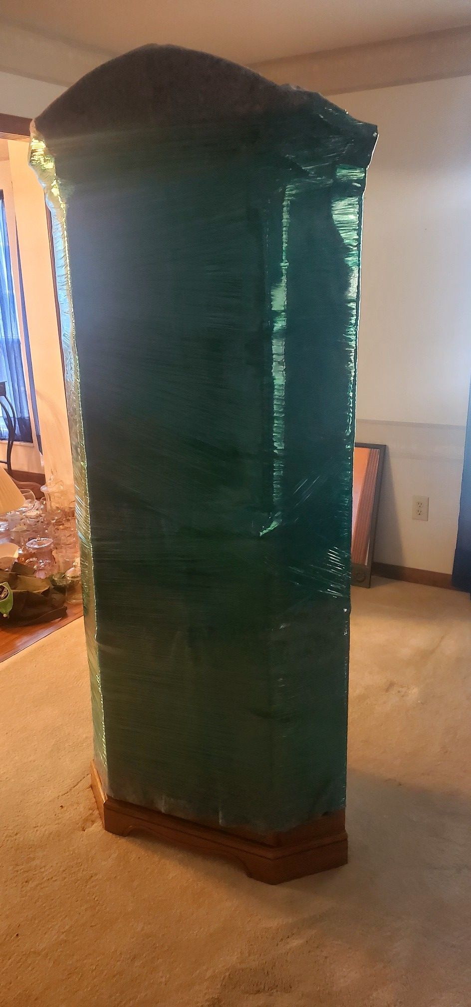 A green cabinet is wrapped in plastic wrap in a living room.
