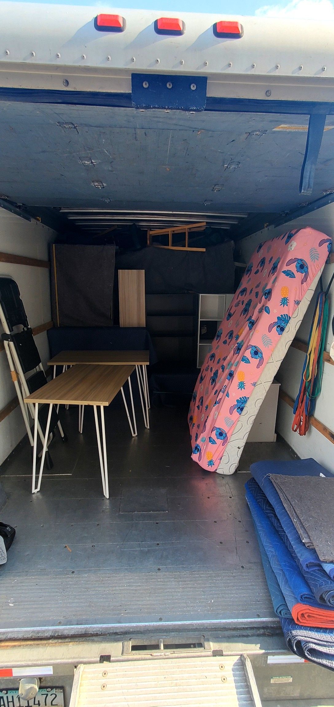 The back of a moving truck filled with furniture and a mattress.