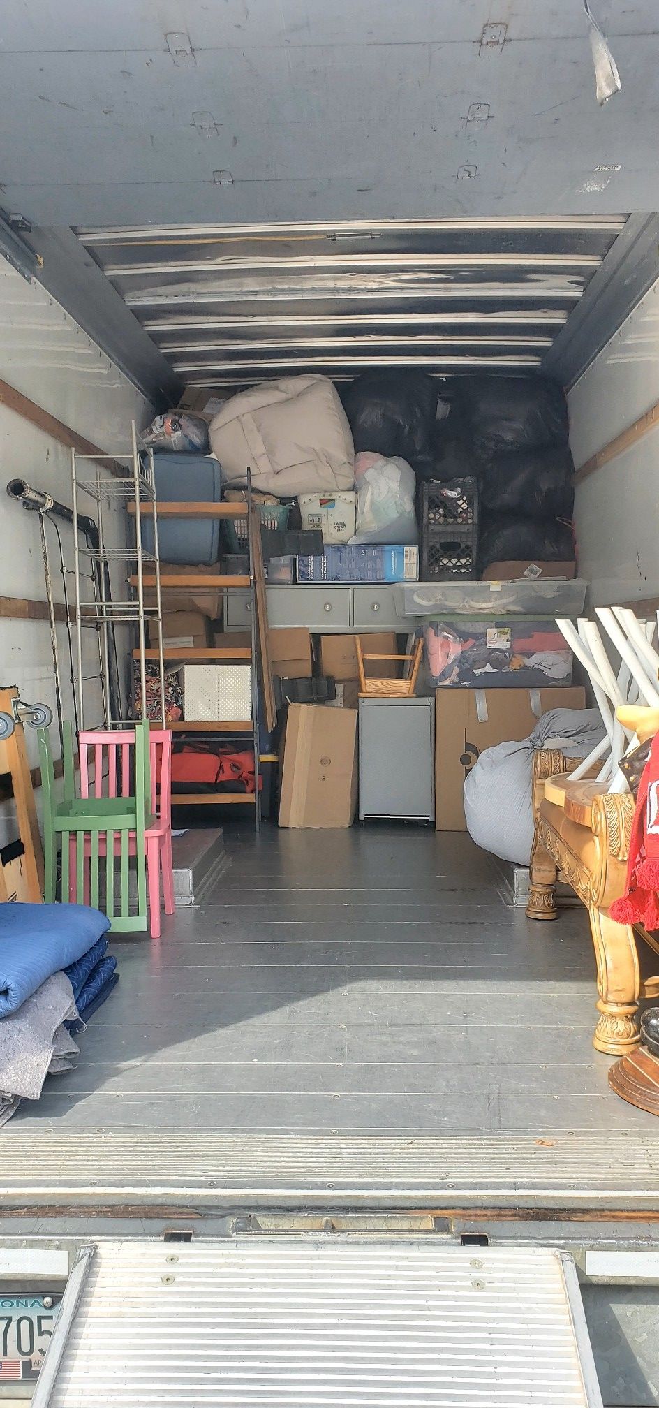 The inside of a moving truck filled with furniture and boxes.