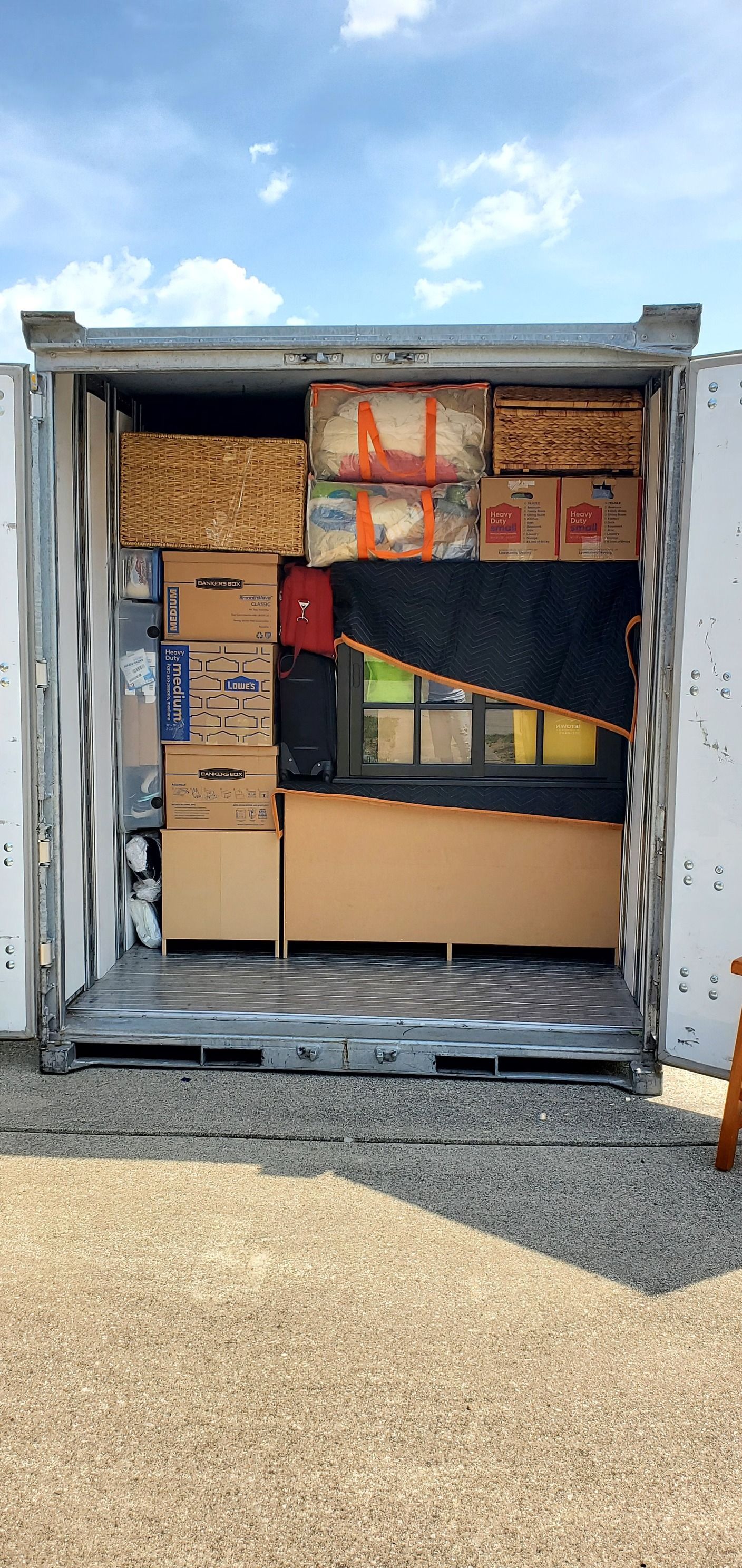 The inside of a shipping container filled with boxes and furniture.