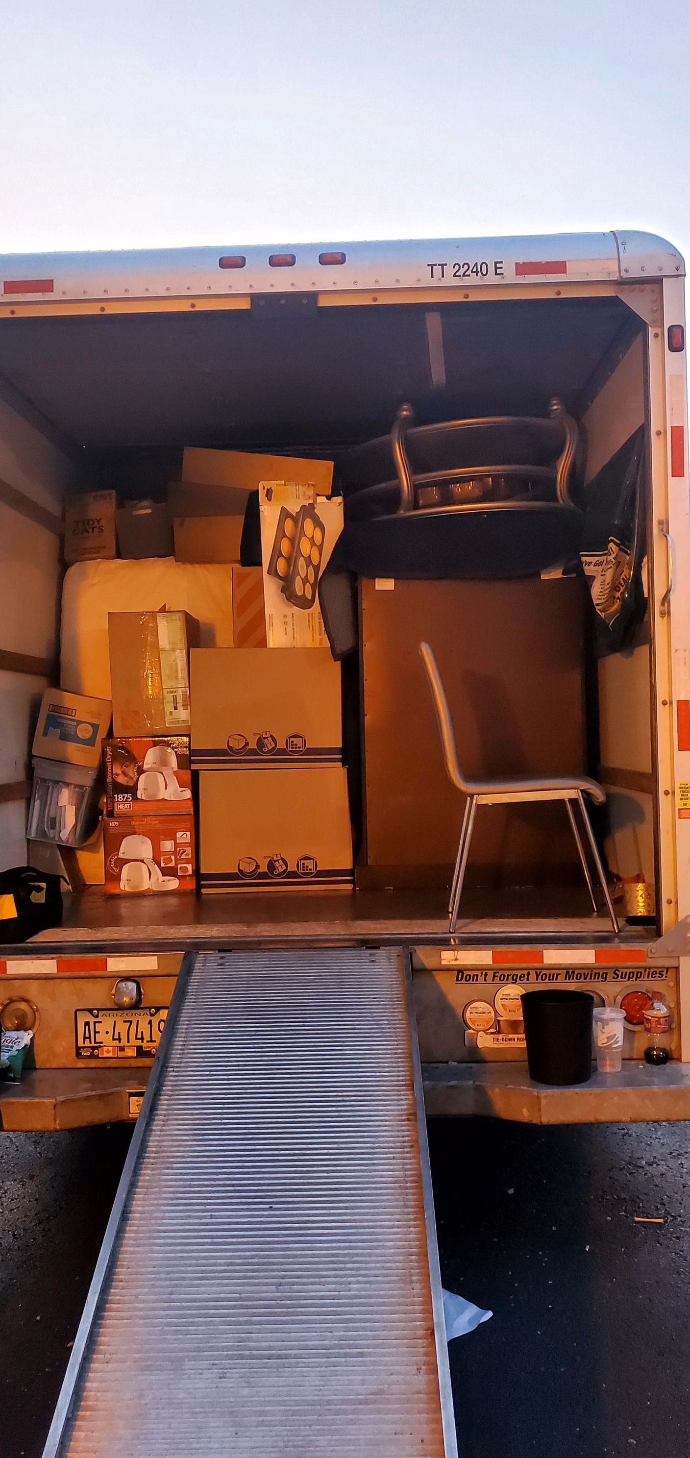 The back of a moving truck filled with boxes and a chair.