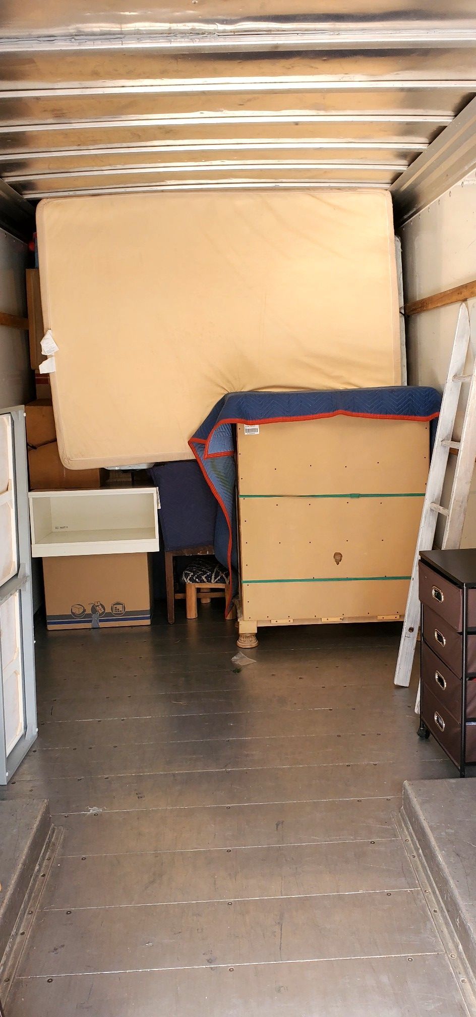 The inside of a moving truck filled with furniture and boxes.