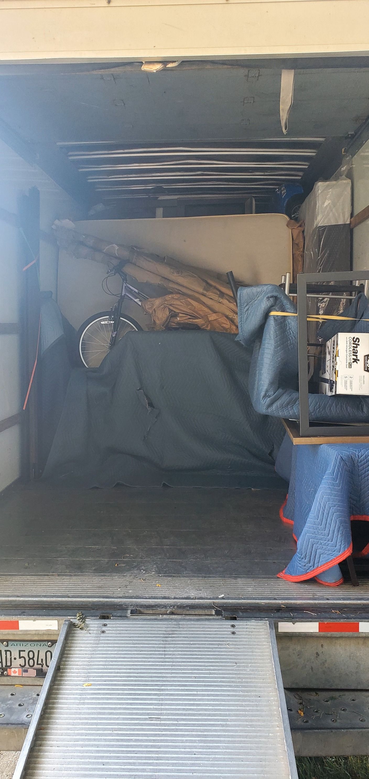 The back of a moving truck filled with furniture and a ramp.