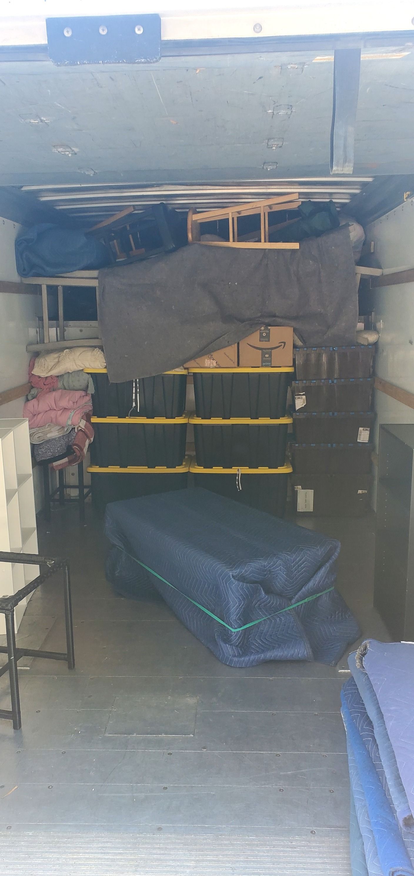 The inside of a moving truck filled with furniture and blankets.