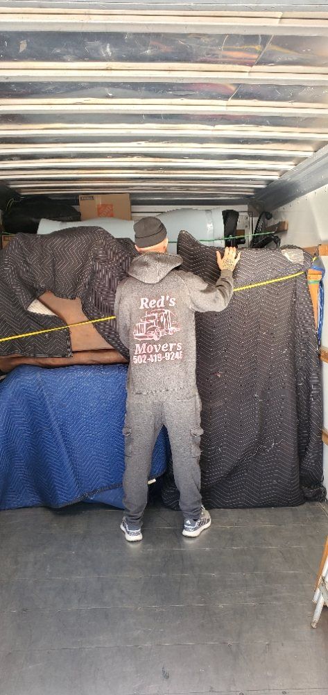 A man is measuring a piece of furniture in a truck.