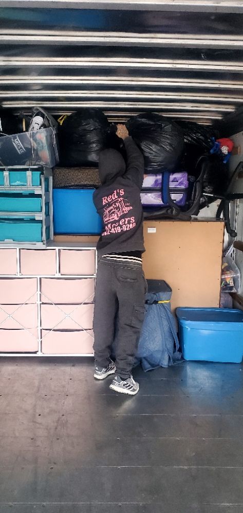 A man is standing in a garage filled with lots of boxes and bags.