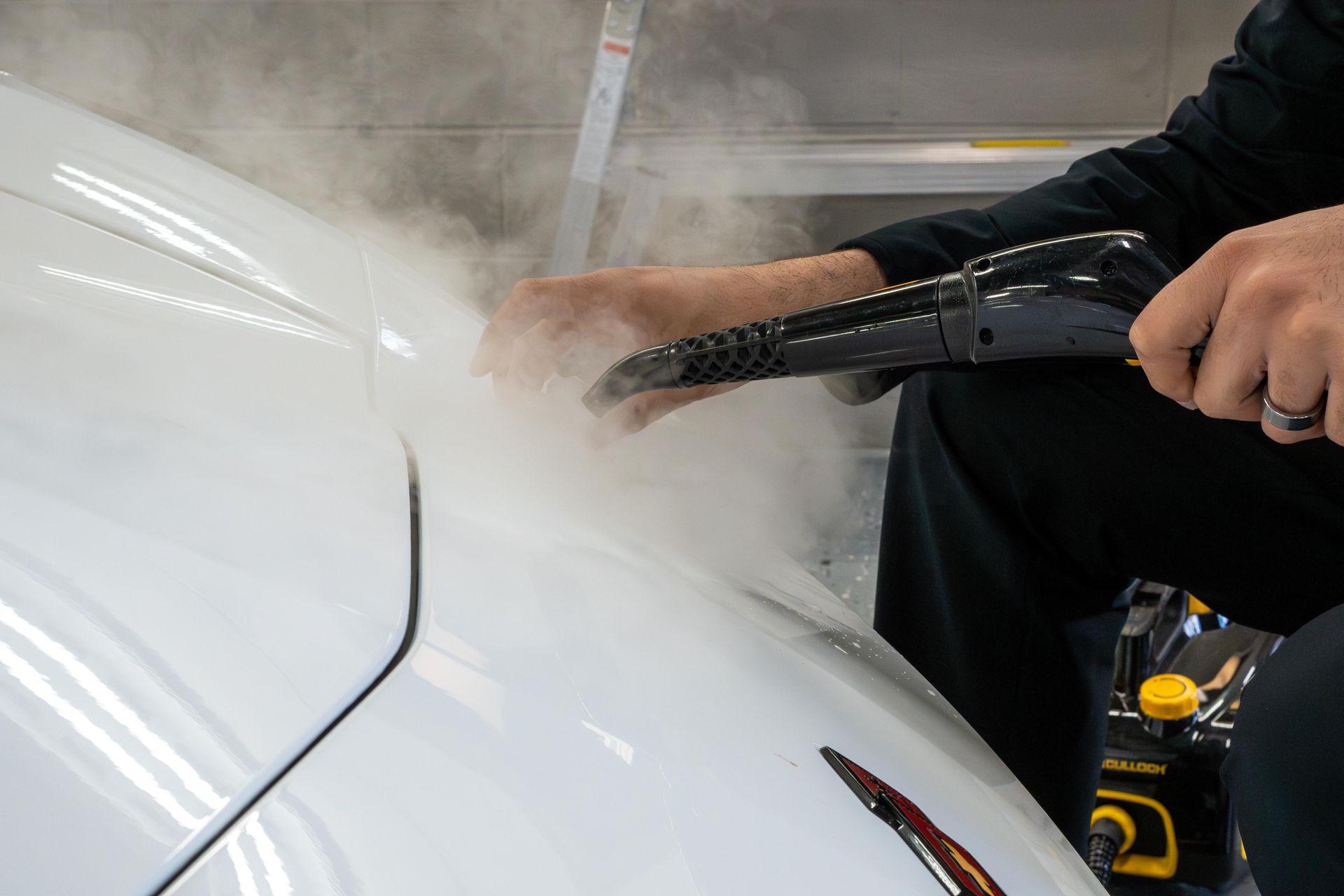 Hands use a metal tool to repair a car headlight in close-up.