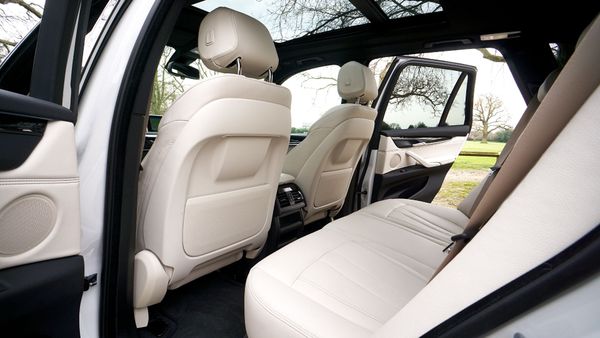 Car interior with white leather seats and open rear door, showing the back seating area.
