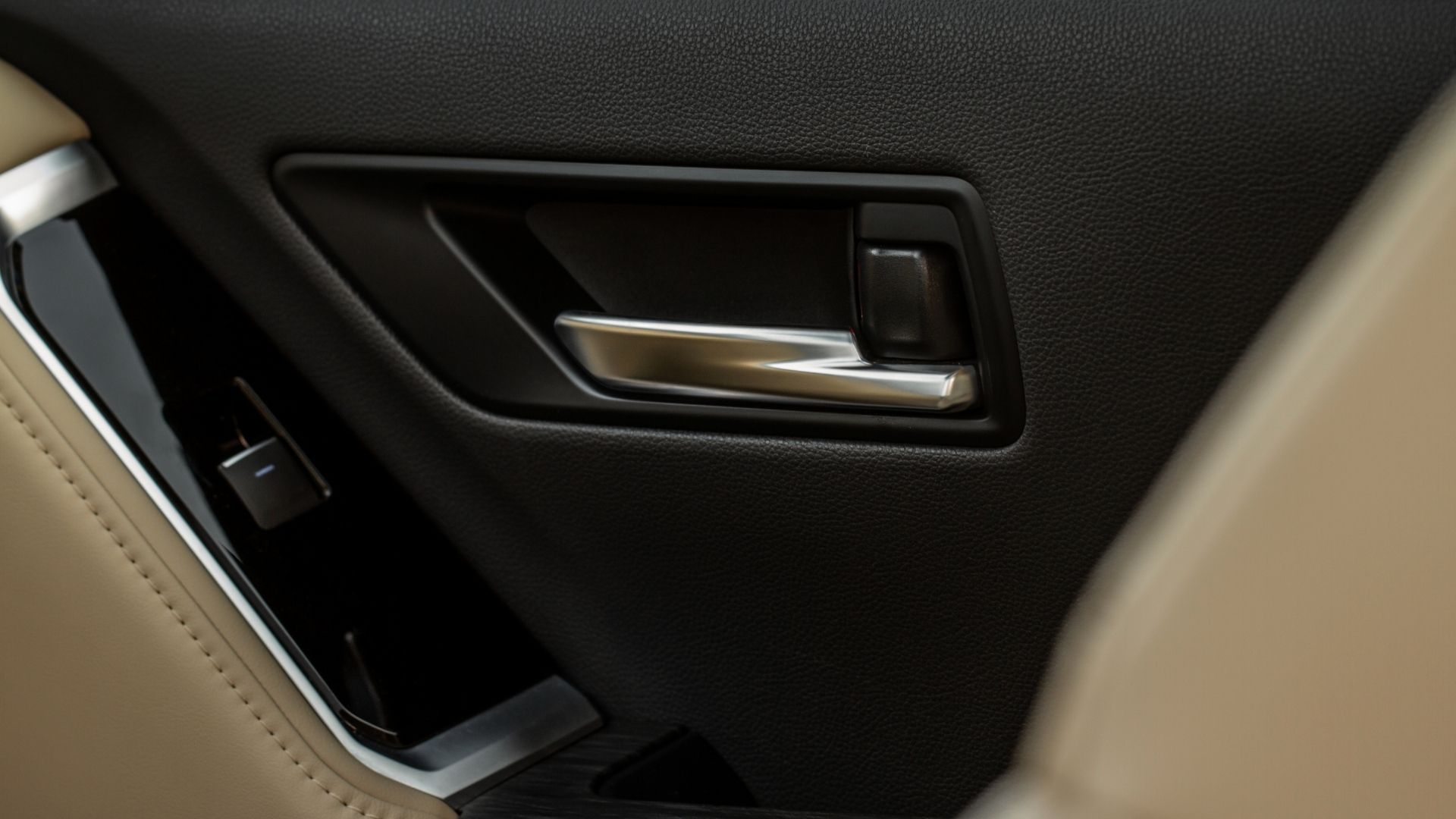 Close-up of a car interior door handle and armrest in black and silver trim