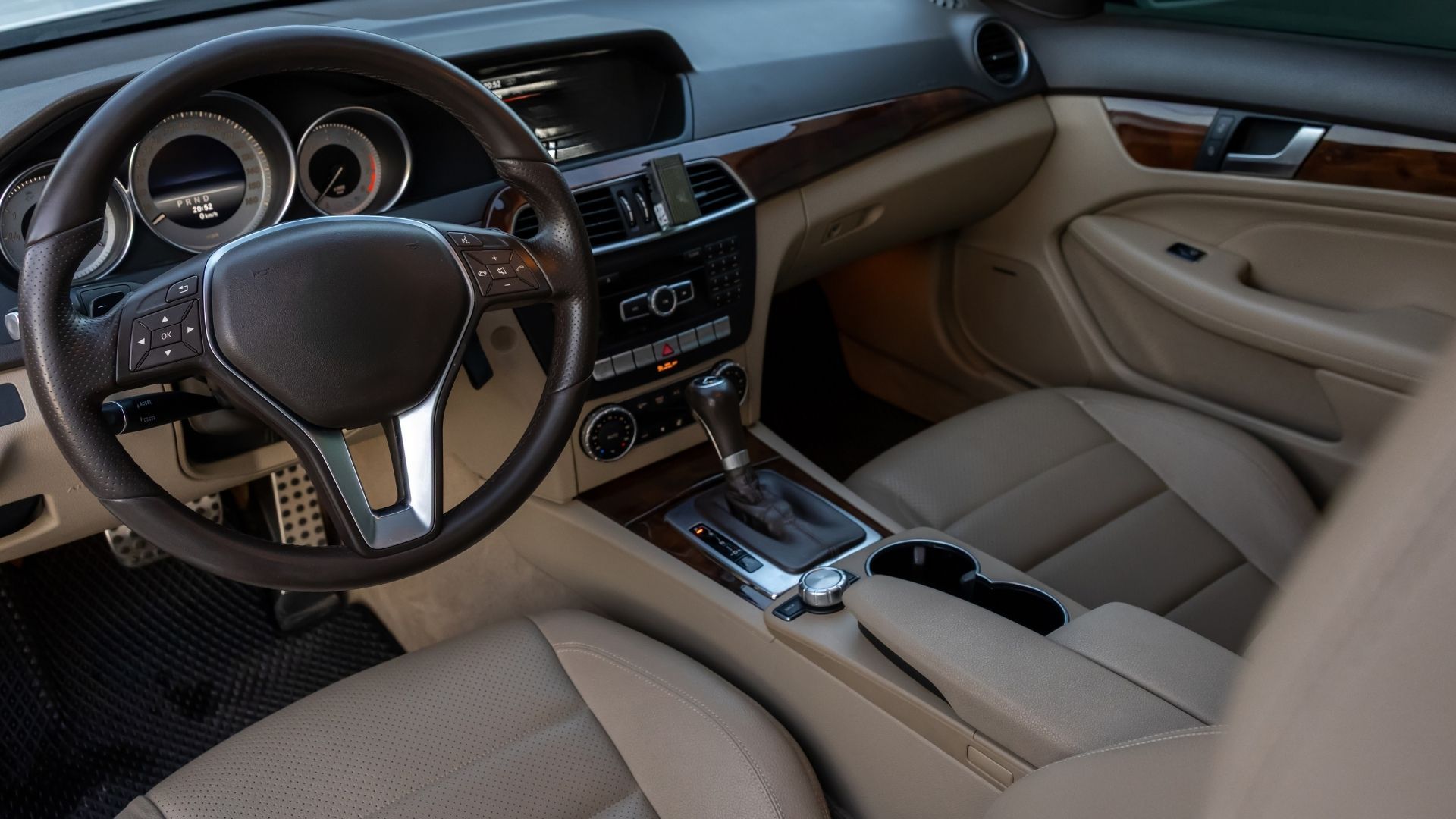 Luxury car interior with tan leather seats, black dashboard, and steering wheel view from the front passenger seat