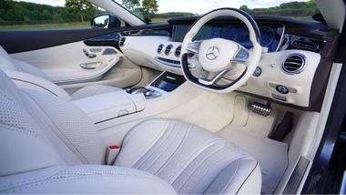 White luxury car interior with leather seats and dashboard, viewed from the passenger side