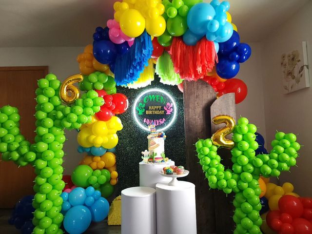 A room decorated with balloons in the shape of cactus and a cake.