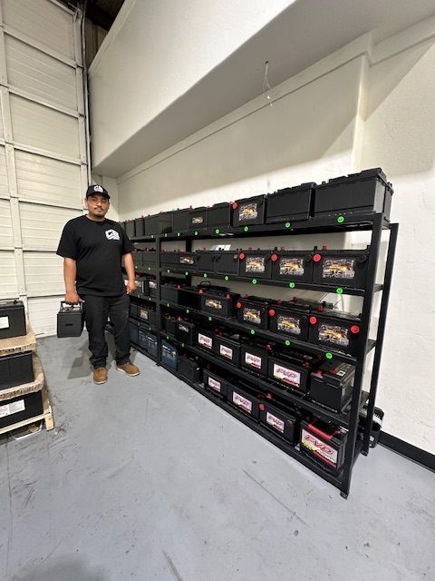 A man is standing in front of a shelf full of batteries.