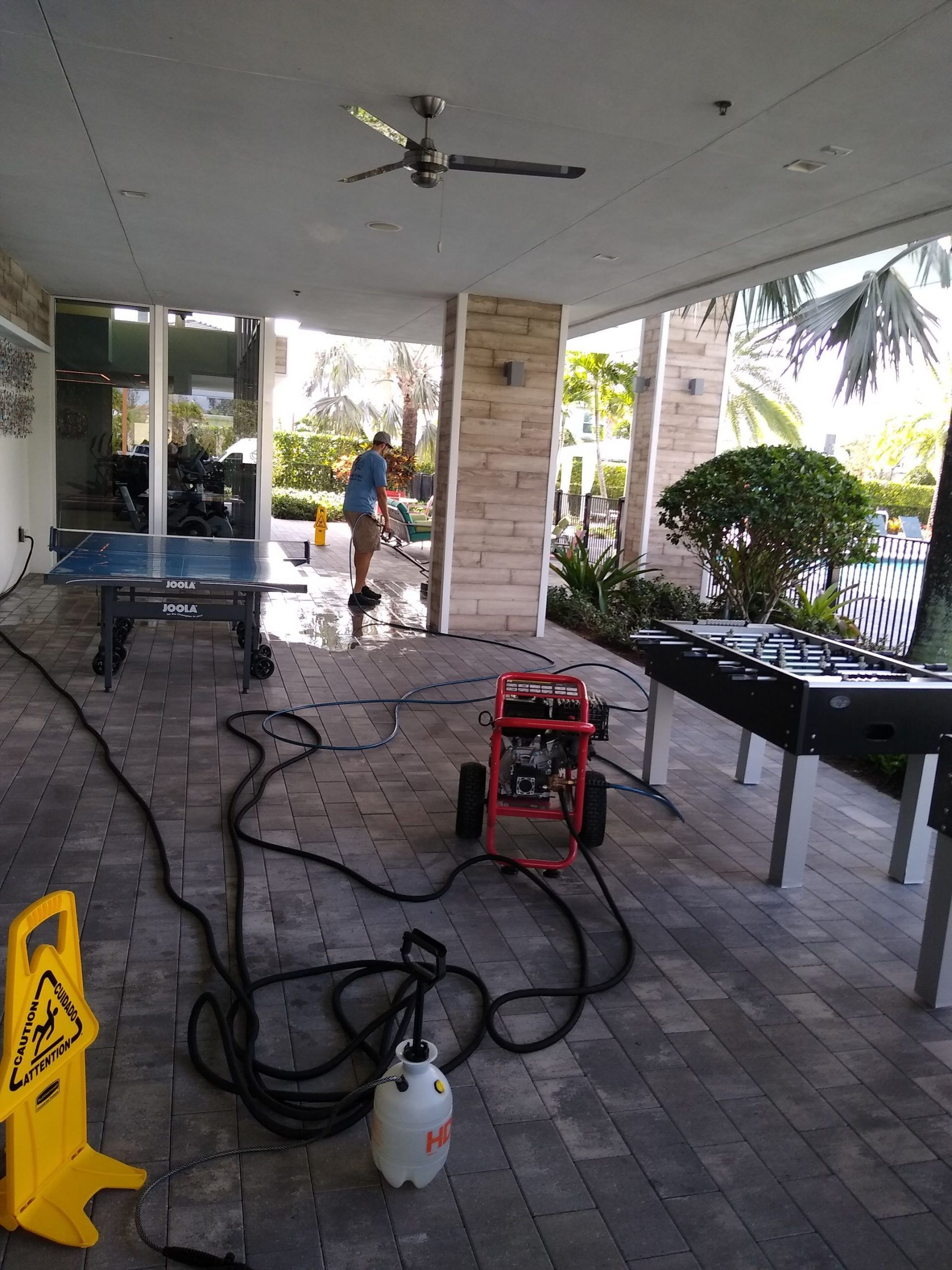 A man is cleaning a pool table on a patio.